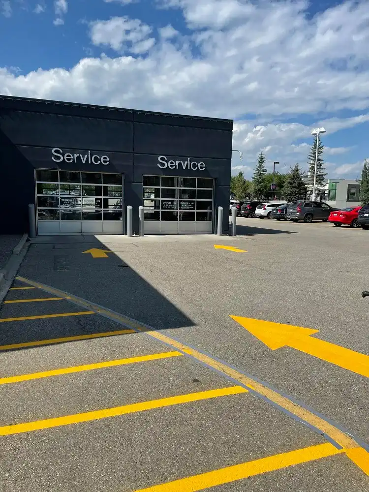 Asphalt parking lot with yellow line painting and service bay doors